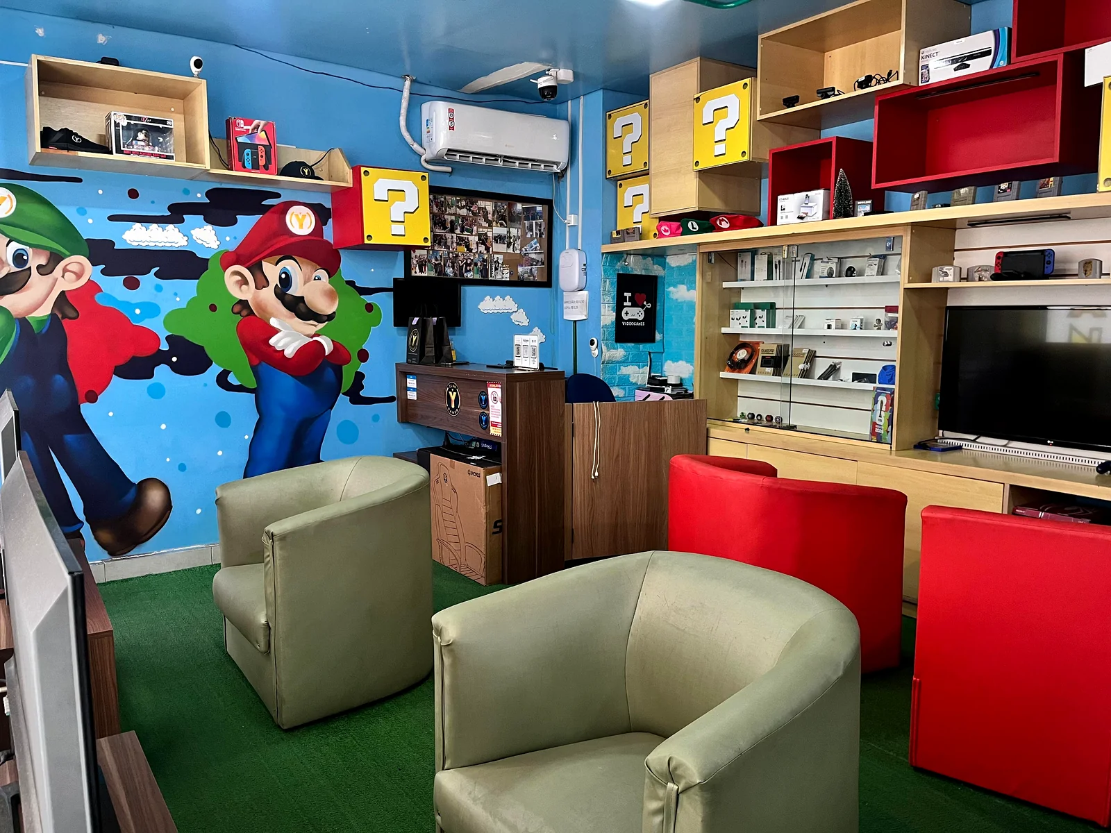 Espaço de convivência da loja CLAN Y GAMER com sofá vermelho e decoração temática Mario.